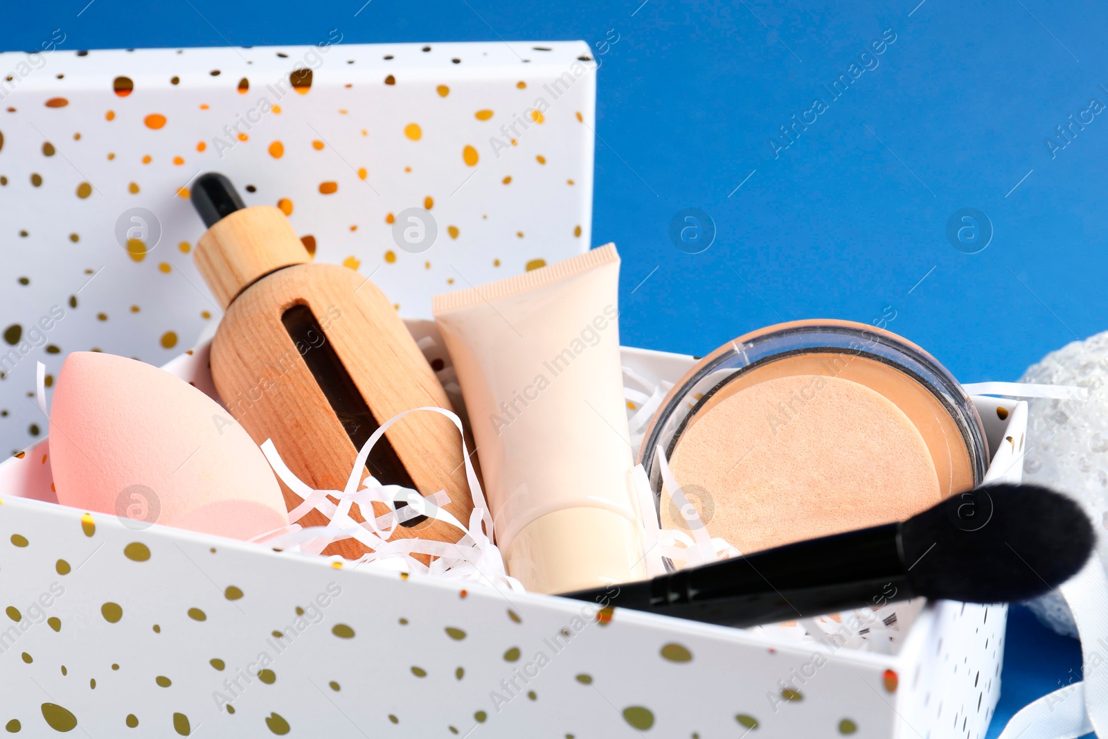 Photo of Cosmetic products in gift box on blue background, closeup. Space for text