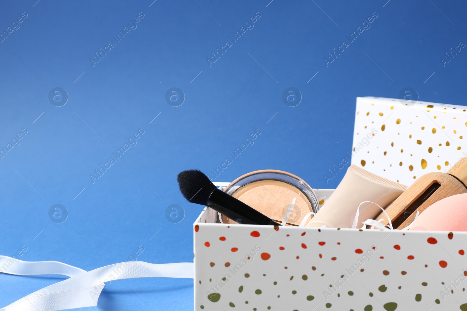 Photo of Cosmetic products in gift box on blue background, closeup. Space for text