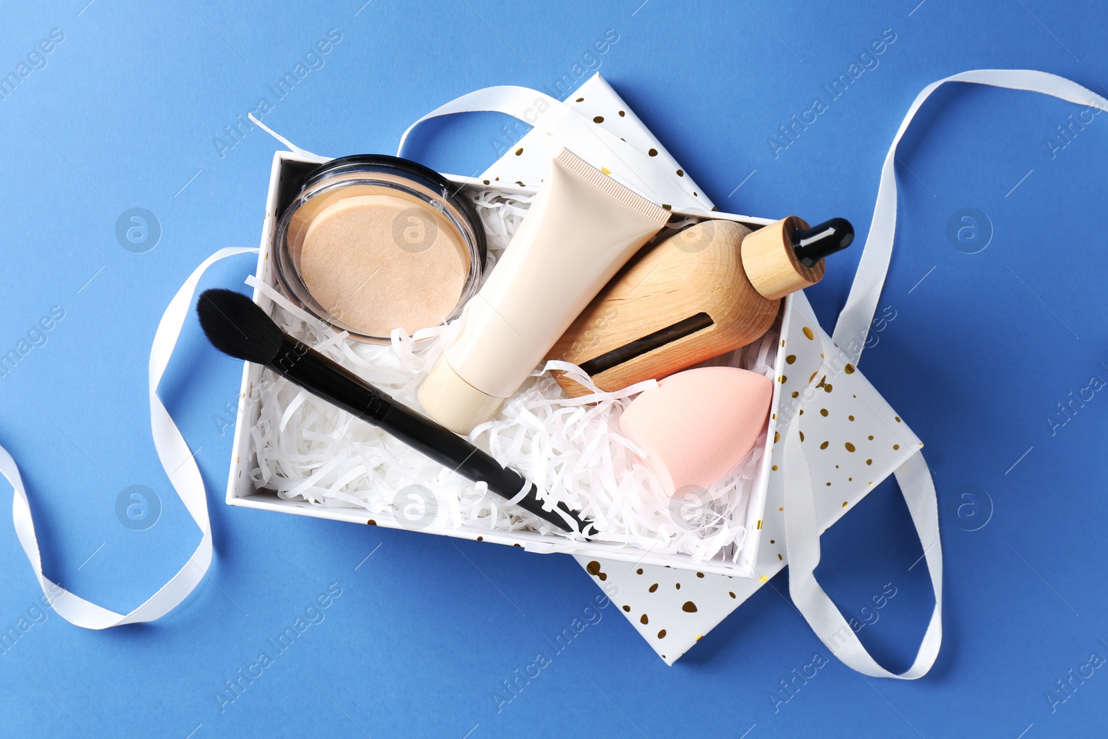 Photo of Cosmetic products in gift box on blue background, top view