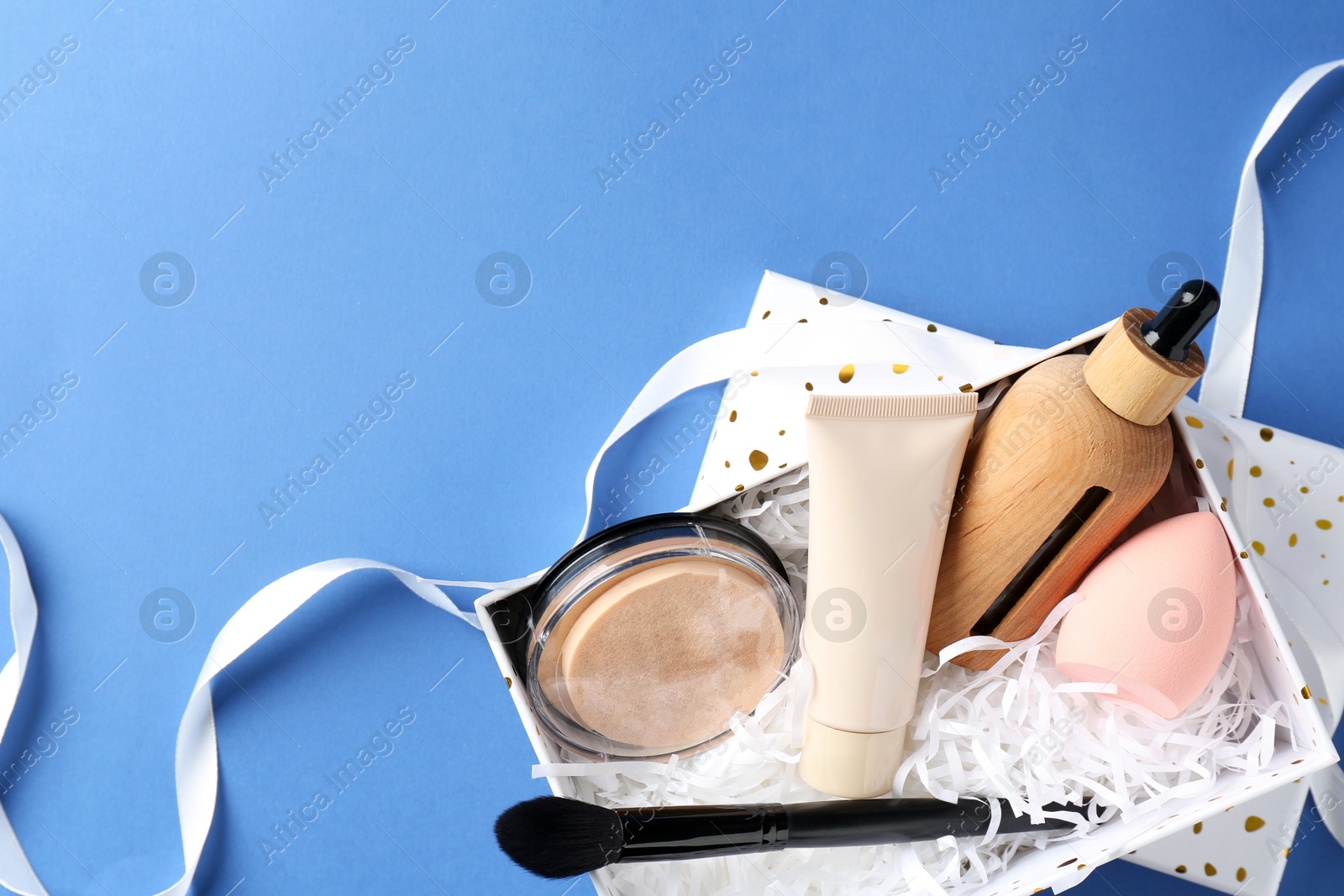 Photo of Cosmetic products in gift box on blue background, top view. Space for text