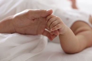 Photo of Mother with her sleeping little baby on bed at home, closeup