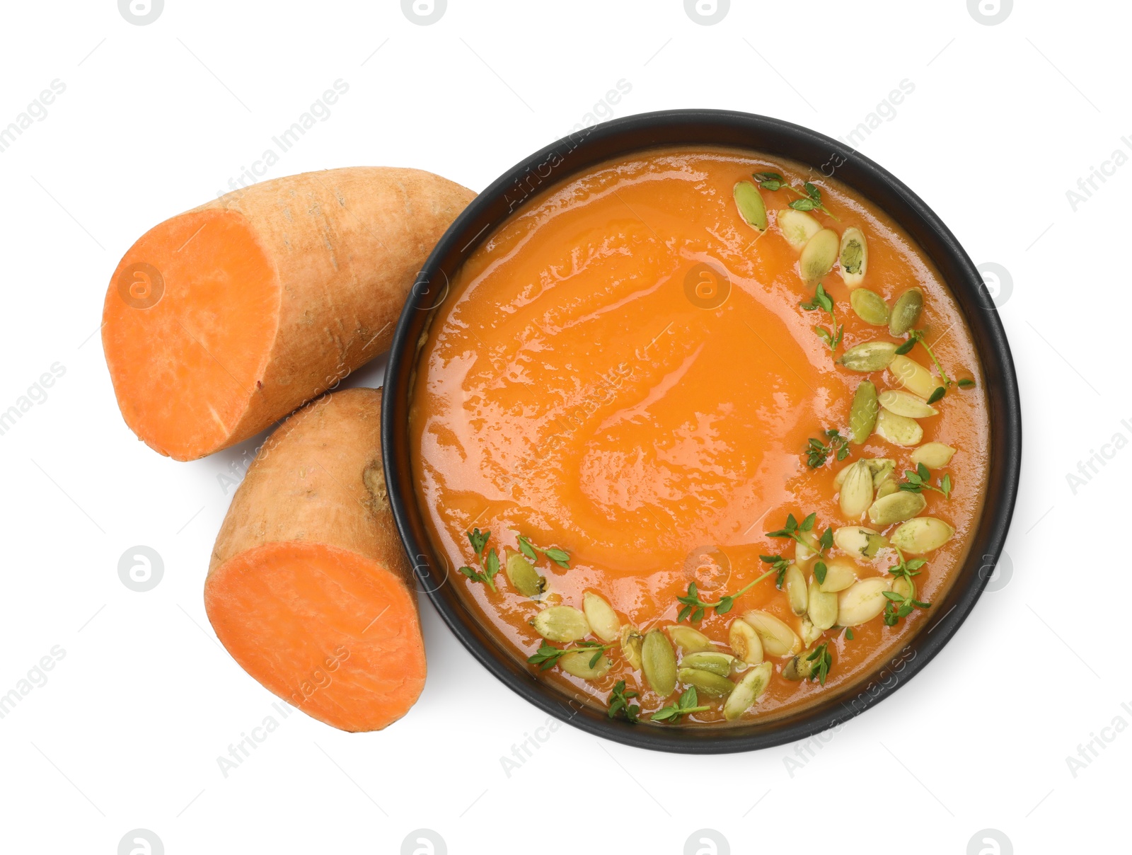 Photo of Delicious sweet potato soup with pumpkin seeds in bowl and fresh vegetable isolated on white, top view