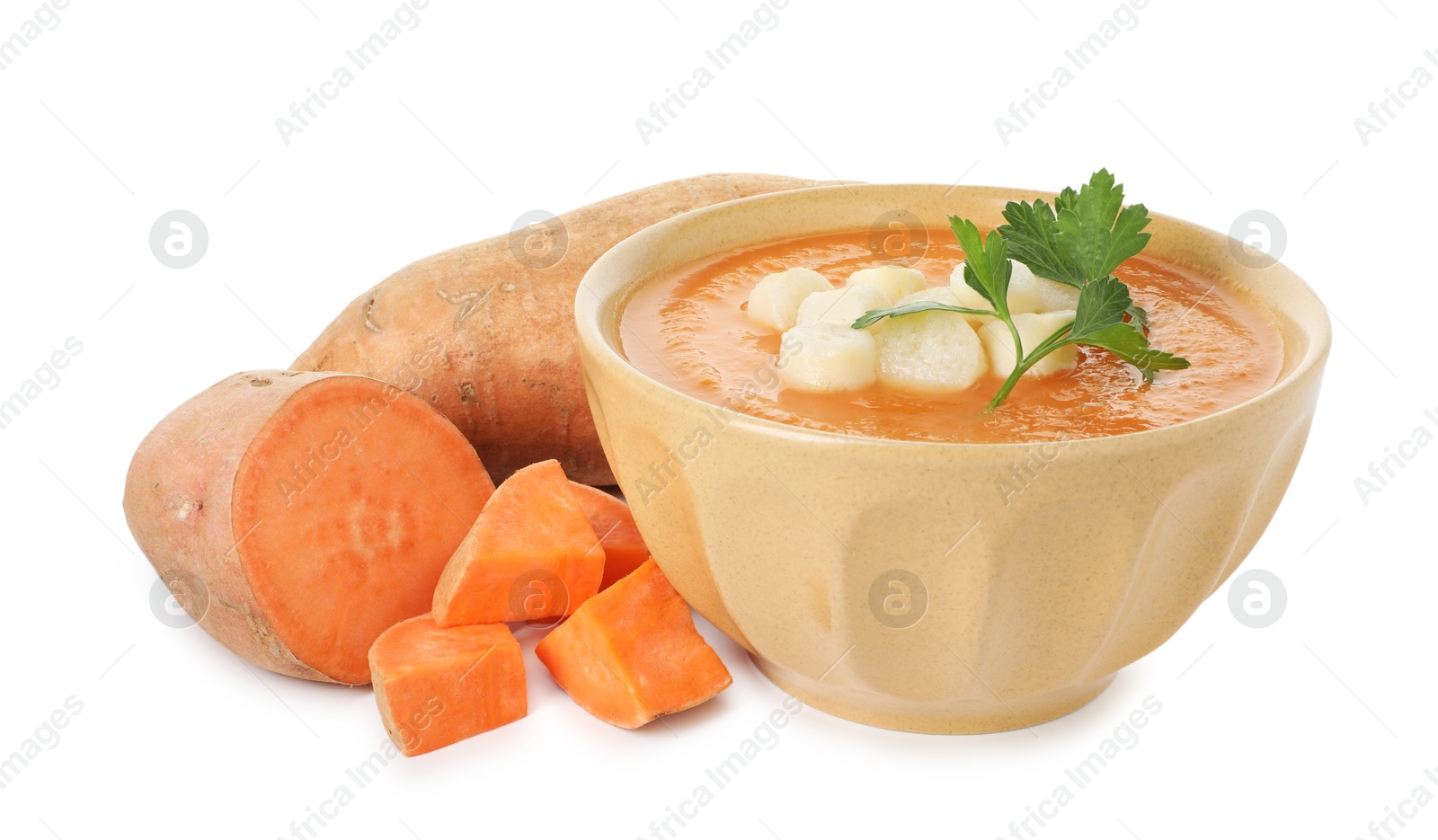 Photo of Delicious sweet potato soup with croutons in bowl and fresh vegetables isolated on white