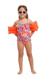 Cute little girl in swimsuit with swim armbands on white background