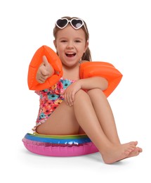 Cute little girl in swimsuit with swim armbands and inflatable ring on white background