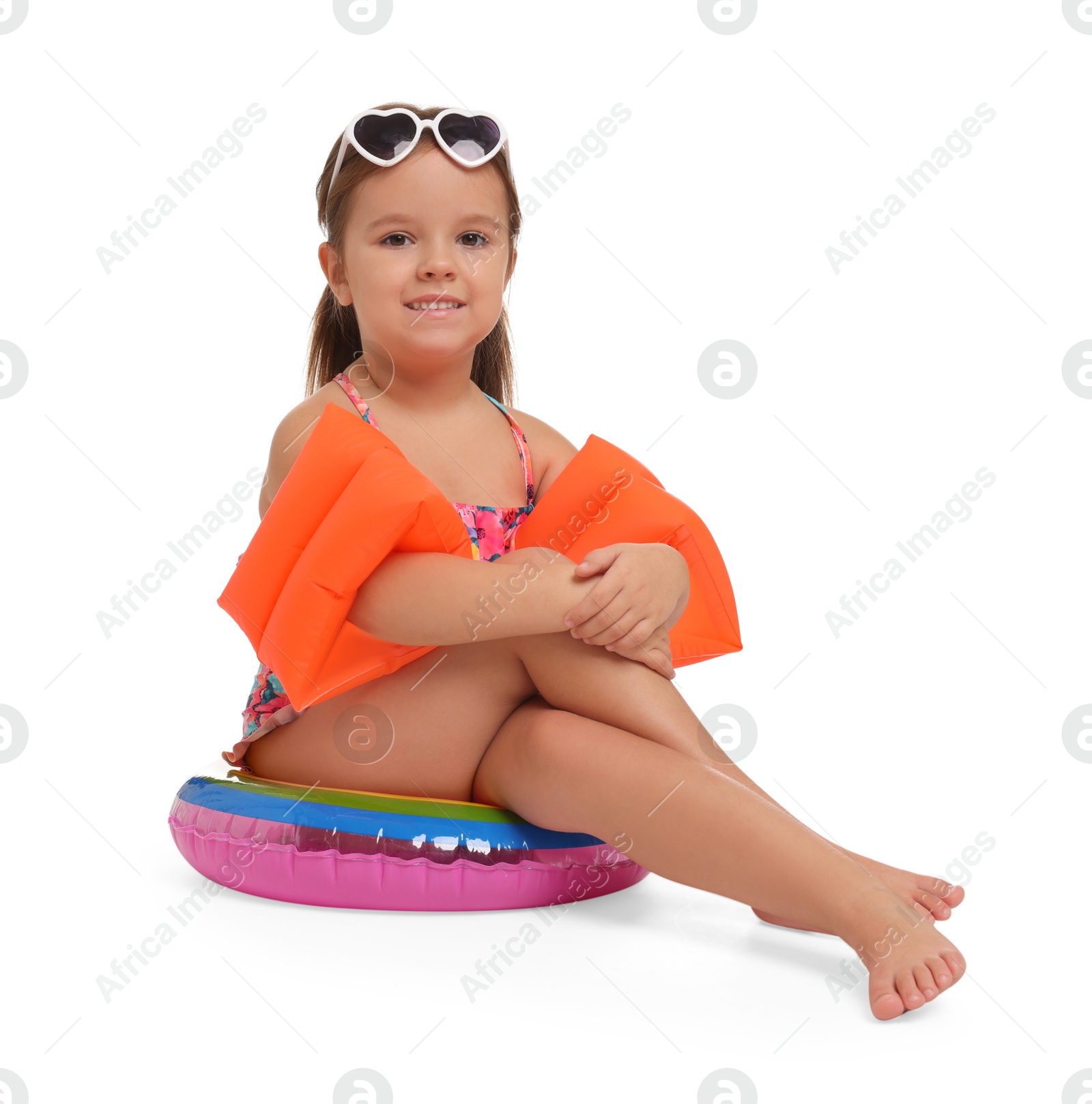 Photo of Cute little girl in swimsuit with swim armbands and inflatable ring on white background