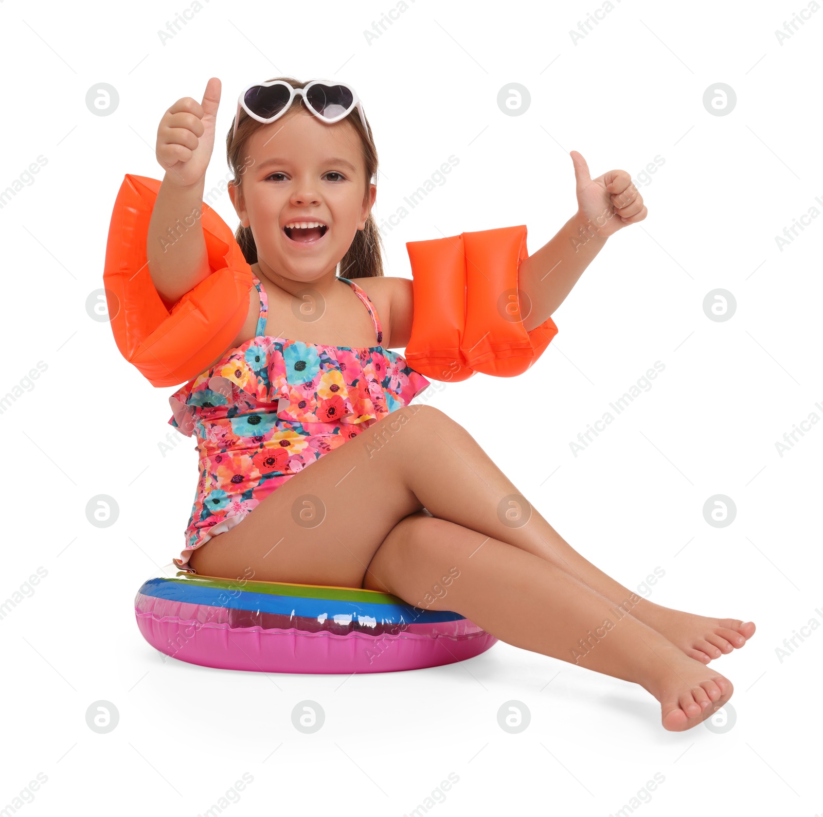 Photo of Cute little girl in swimsuit with swim armbands and inflatable ring on white background