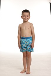 Photo of Cute little boy in beachwear on white background