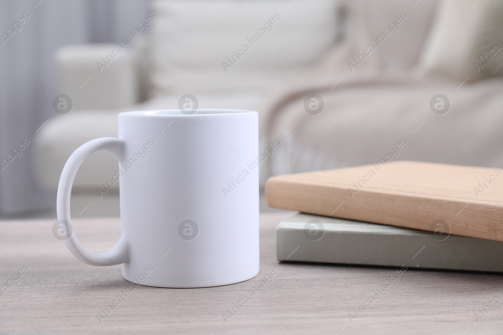 Photo of Blank ceramic mug and notebooks on wooden table. Mockup for design