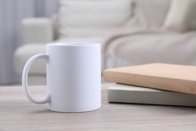 Blank ceramic mug and notebooks on wooden table. Mockup for design