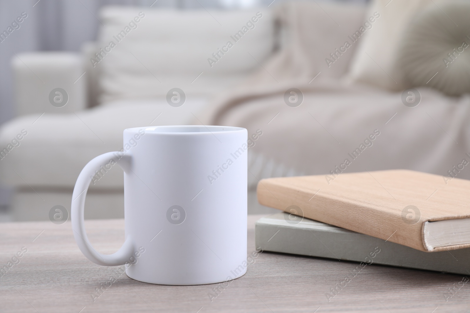 Photo of Blank ceramic mug and notebooks on wooden table. Mockup for design