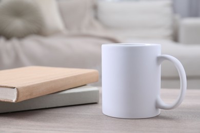 Photo of Blank ceramic mug and notebooks on wooden table. Mockup for design