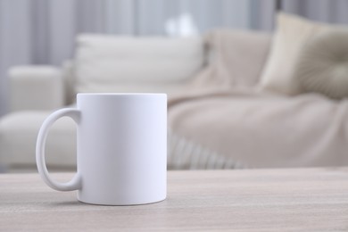 Photo of One blank ceramic mug on white wooden table. Mockup for design