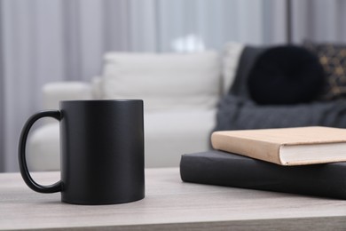 Photo of Blank black ceramic mug and notebooks on wooden table. Mockup for design