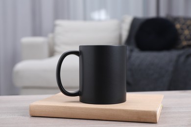 Photo of Blank black ceramic mug and notebook on wooden table. Mockup for design