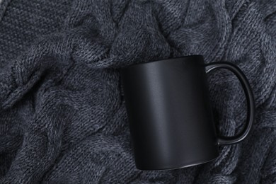 Photo of One blank ceramic mug on black fabric, top view. Mockup for design