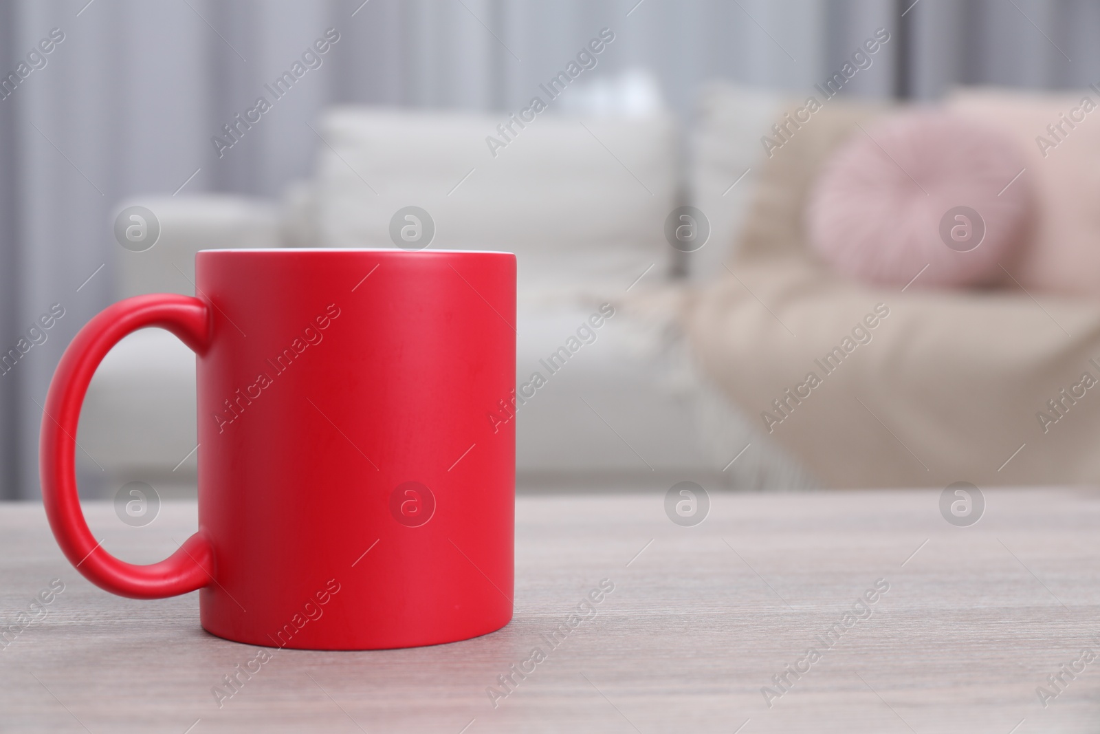 Photo of One blank red ceramic mug on white wooden table. Mockup for design