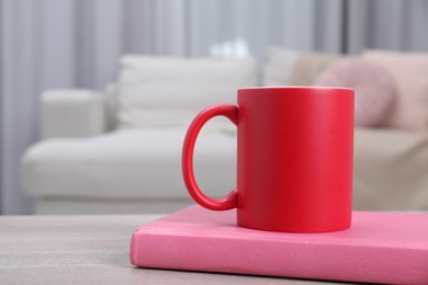 Photo of Blank red ceramic mug and notebook on wooden table. Mockup for design