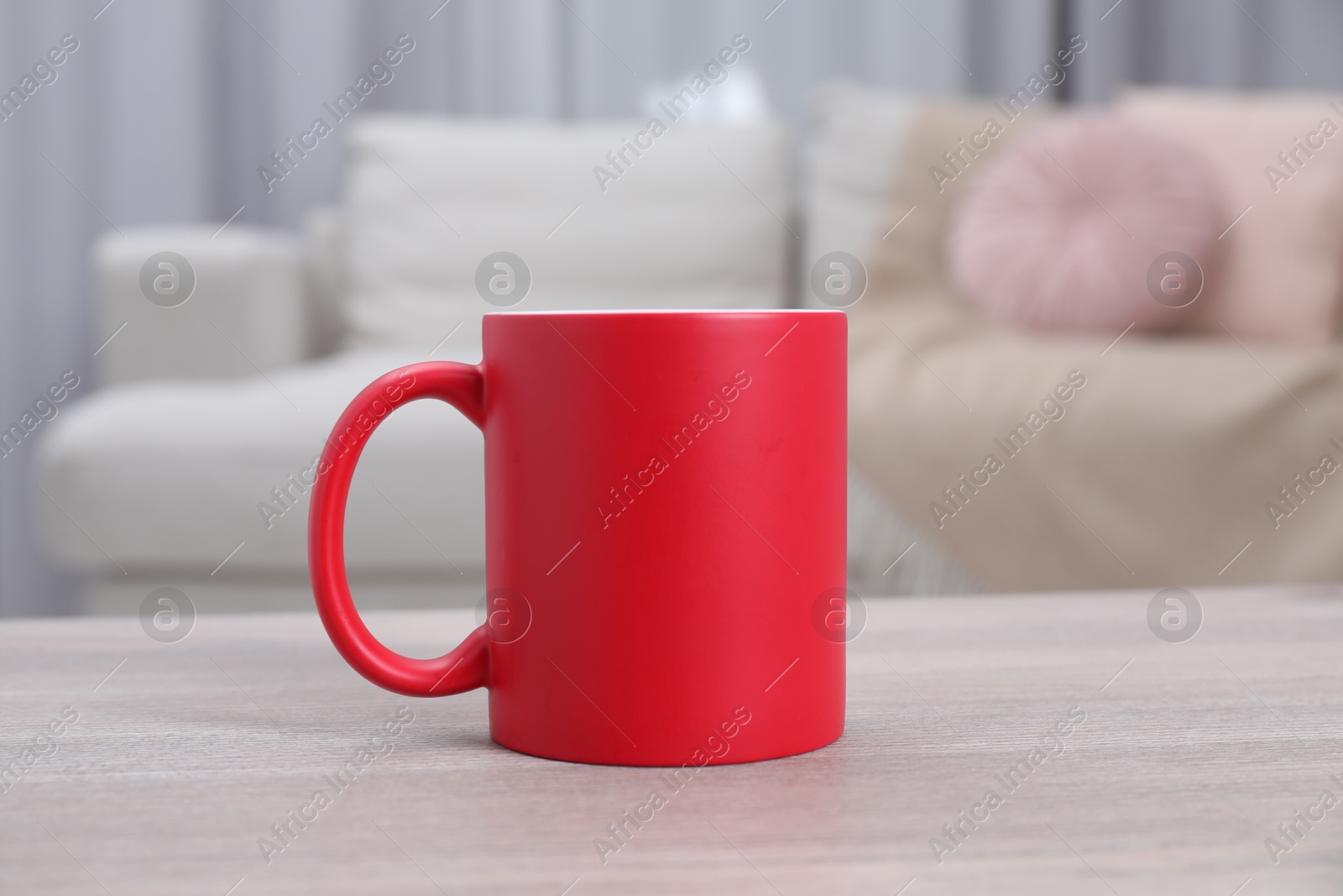 Photo of One blank red ceramic mug on white wooden table. Mockup for design