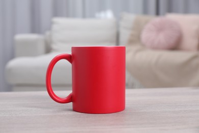 Photo of One blank red ceramic mug on white wooden table. Mockup for design