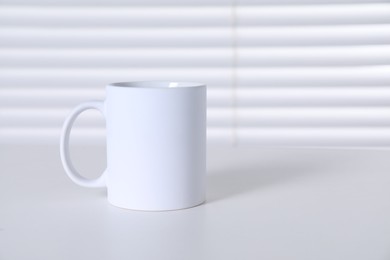 Photo of One blank ceramic mug on white table. Mockup for design