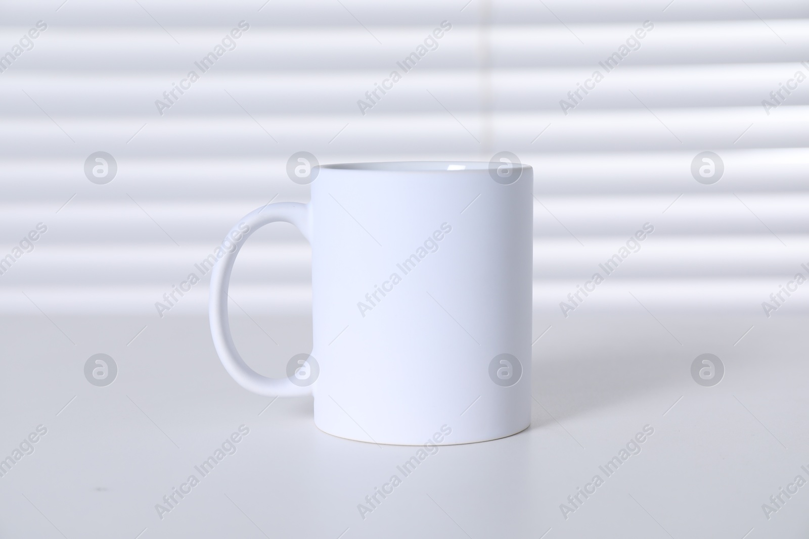 Photo of One blank ceramic mug on white table. Mockup for design