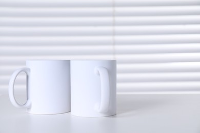 Blank ceramic mugs on white table. Mockup for design