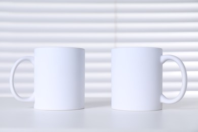 Blank ceramic mugs on white table. Mockup for design