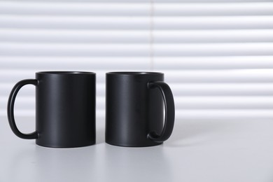 Blank black ceramic mugs on white table. Mockup for design