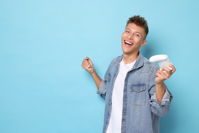 Photo of Happy young man with controller on light blue background, space for text