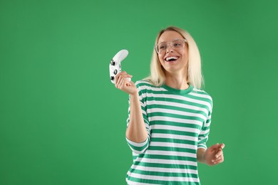 Happy woman with controller on green background, space for text