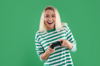 Photo of Happy woman playing video games with controller on green background