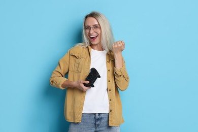 Photo of Happy woman with controller on light blue background