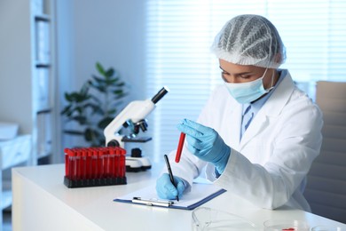 Laboratory testing. Doctor with blood sample working at table indoors