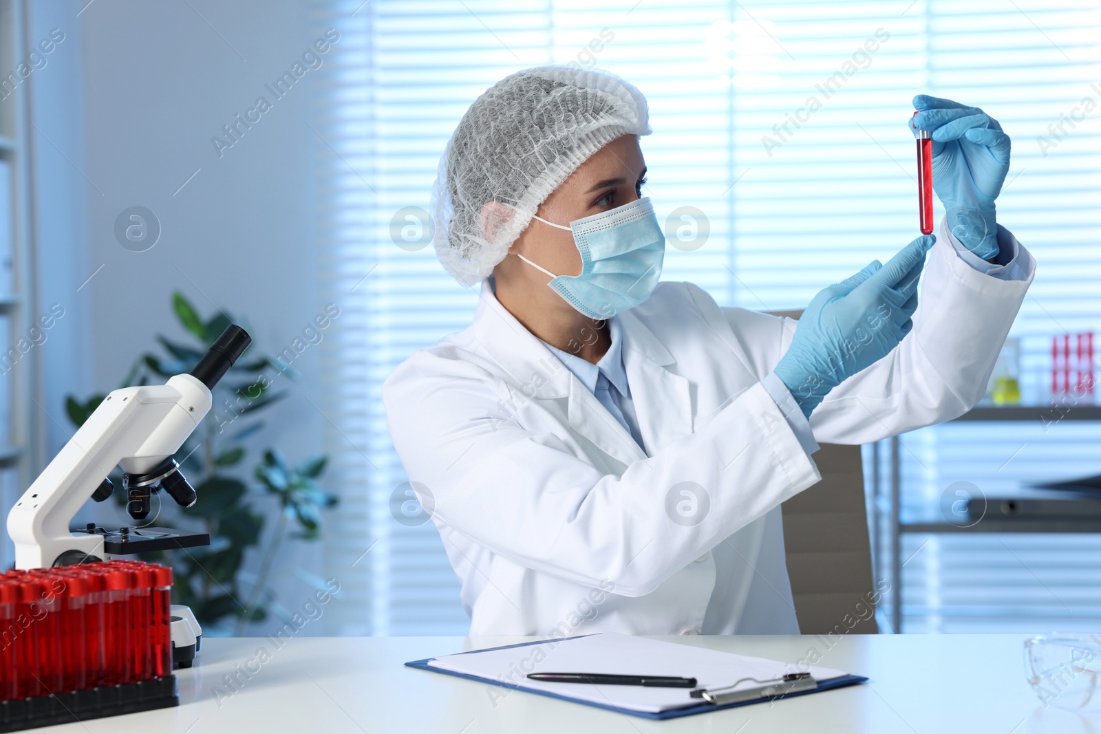 Photo of Laboratory testing. Doctor holding test tube with blood sample at table indoors