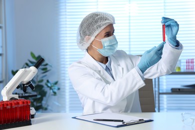 Laboratory testing. Doctor holding test tube with blood sample at table indoors