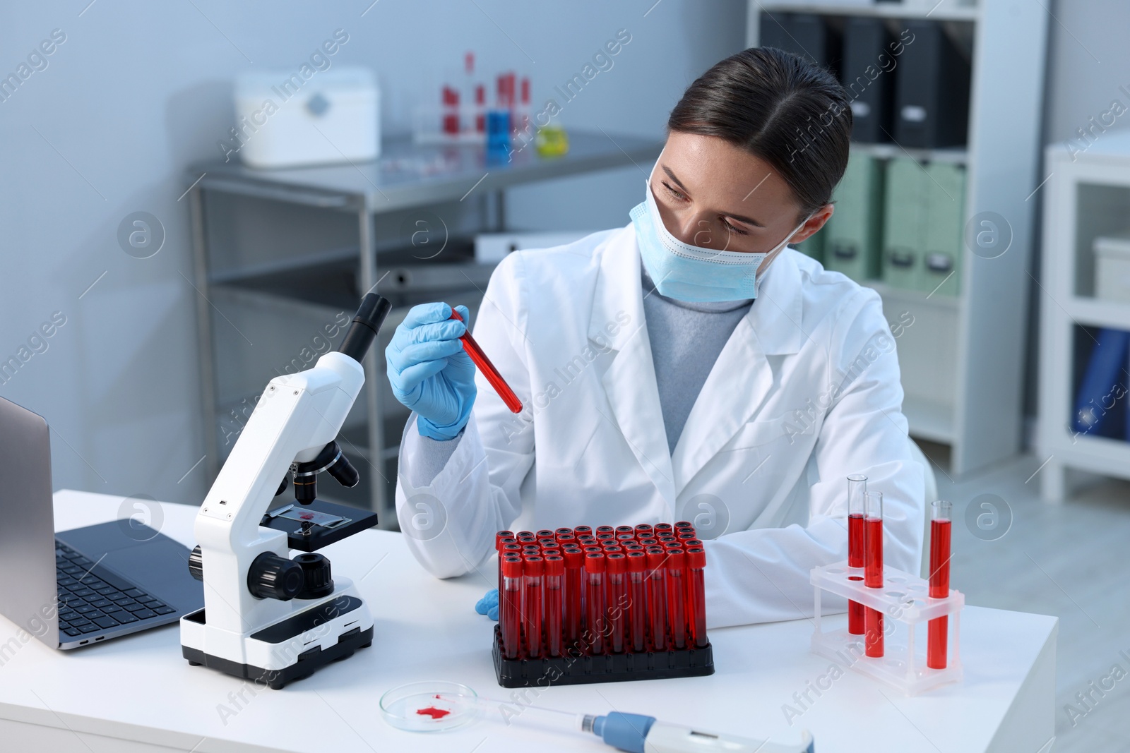 Photo of Laboratory testing. Doctor holding test tube with blood sample at table indoors