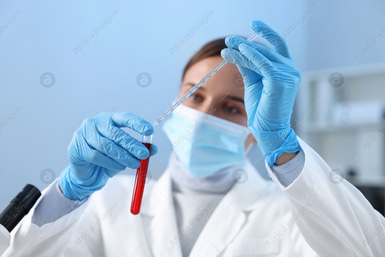 Photo of Laboratory testing. Doctor dripping blood sample into test tube indoors, selective focus