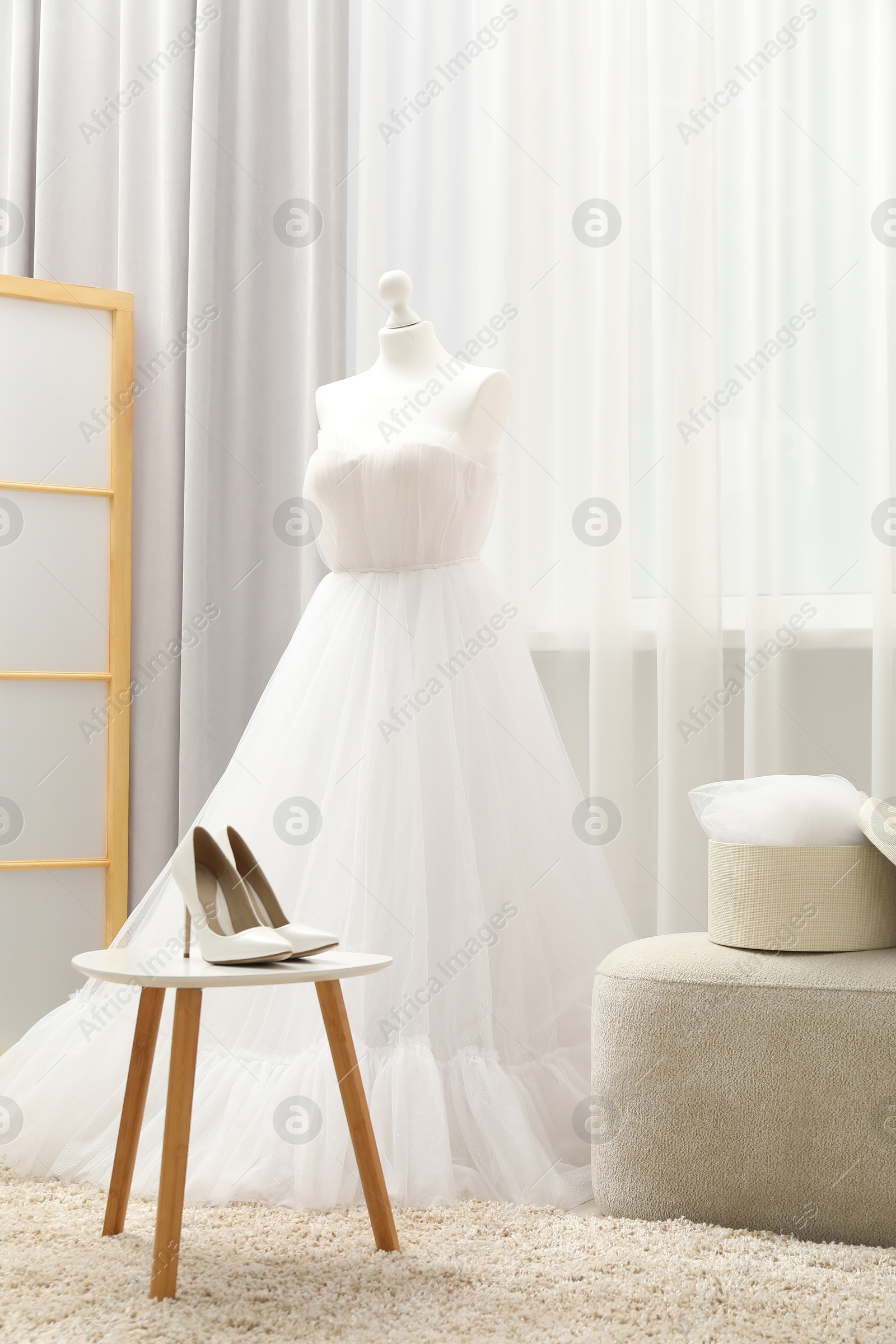 Photo of Beautiful wedding dress on mannequin and shoes in boutique