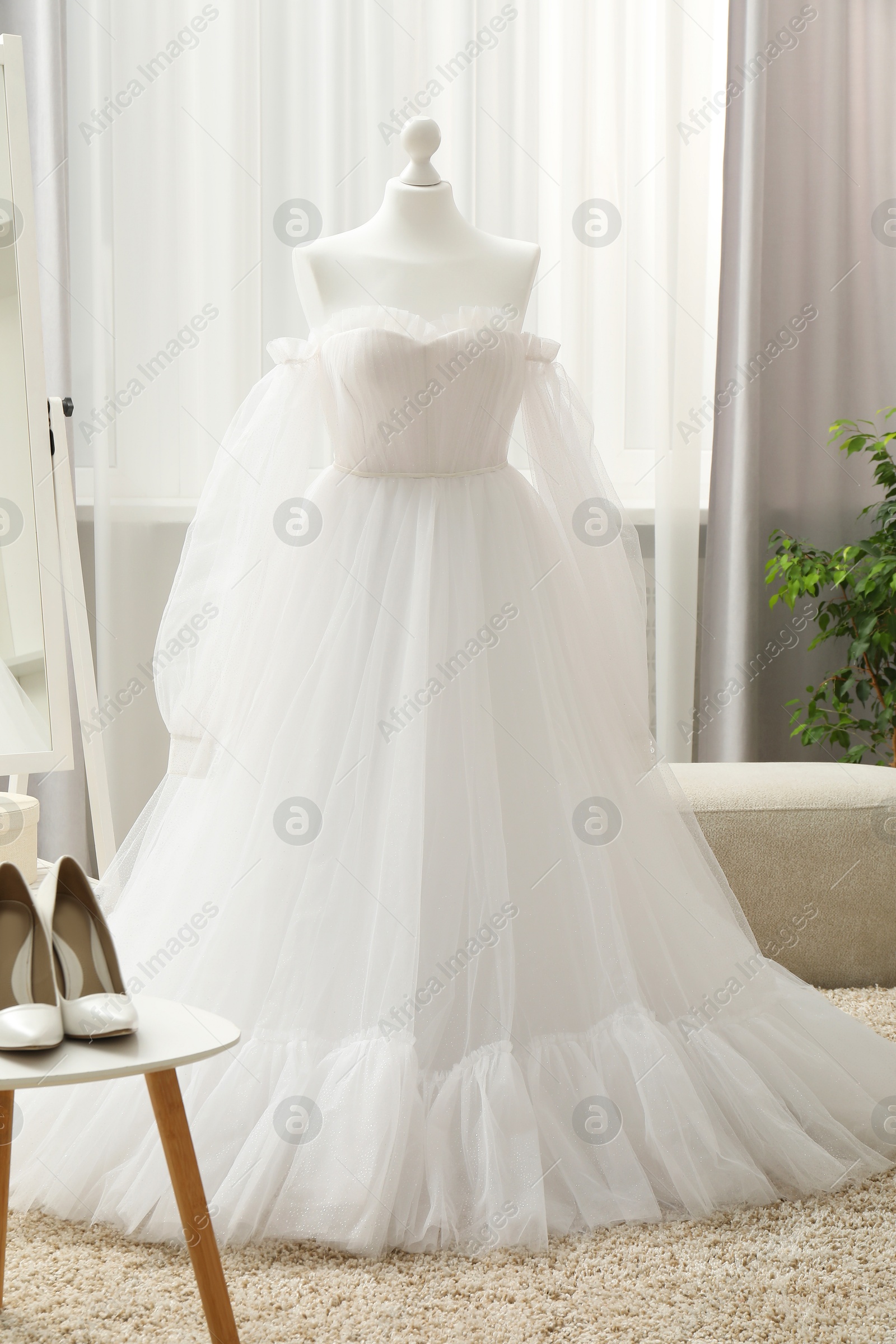 Photo of Beautiful wedding dress on mannequin and shoes in boutique