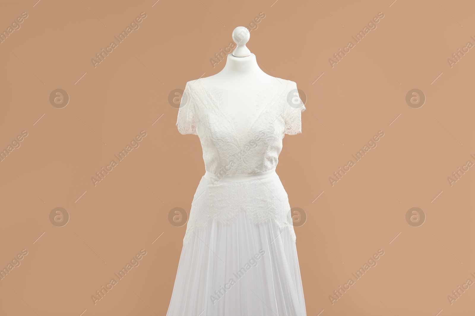 Photo of Mannequin with beautiful wedding dress on pale brown background