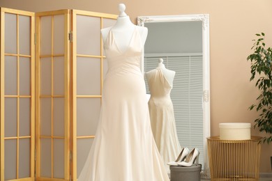 Beautiful wedding dress on mannequin and shoes in boutique