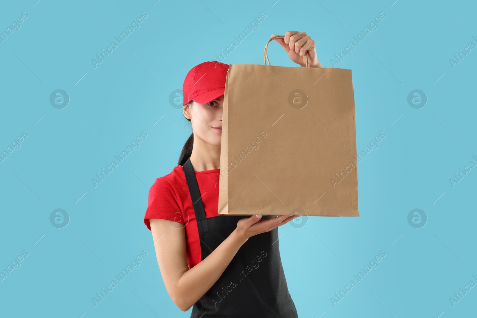 Photo of Fast-food worker with paper bag on light blue background