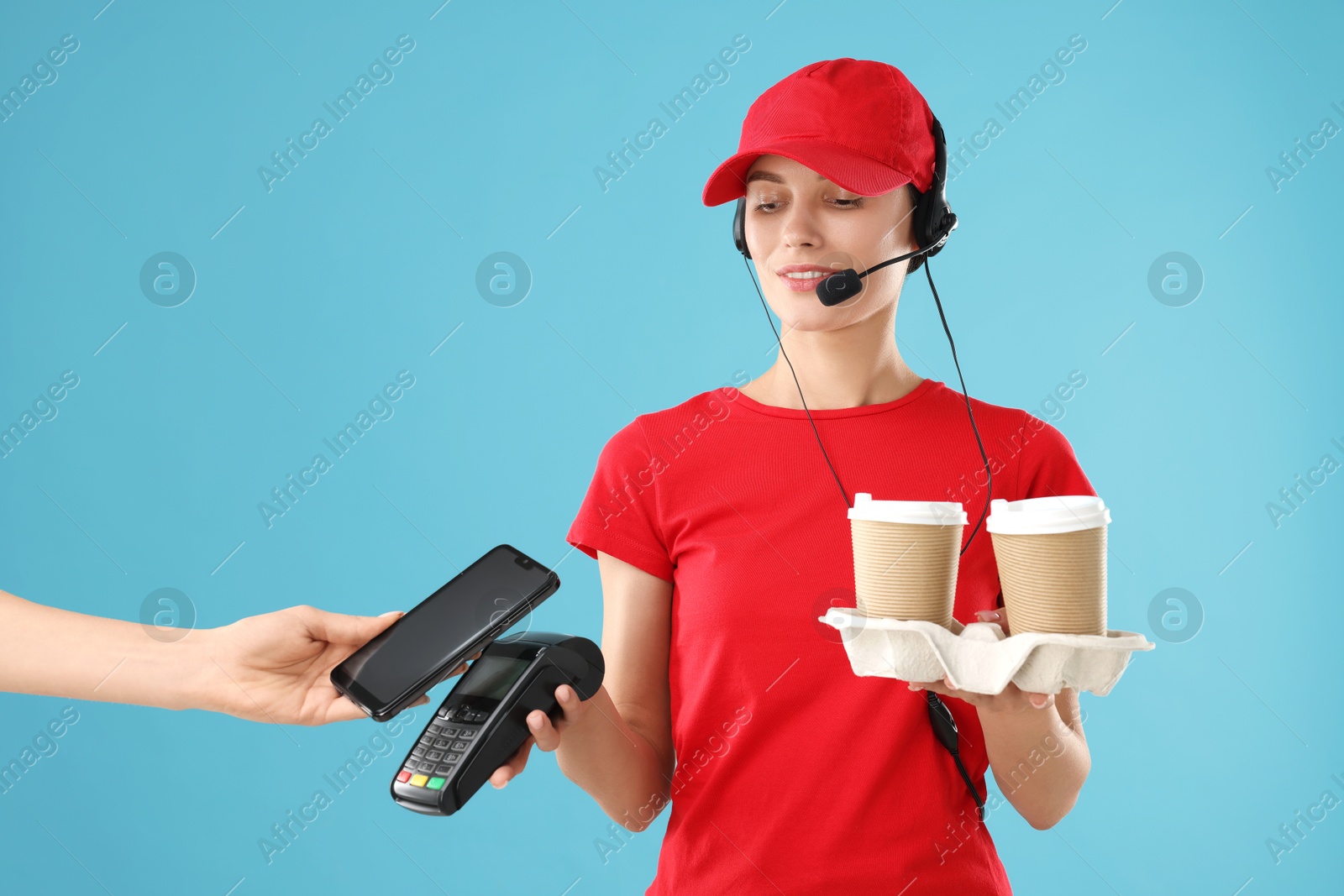 Photo of Fast-food worker taking payment from client via terminal on light blue background, closeup