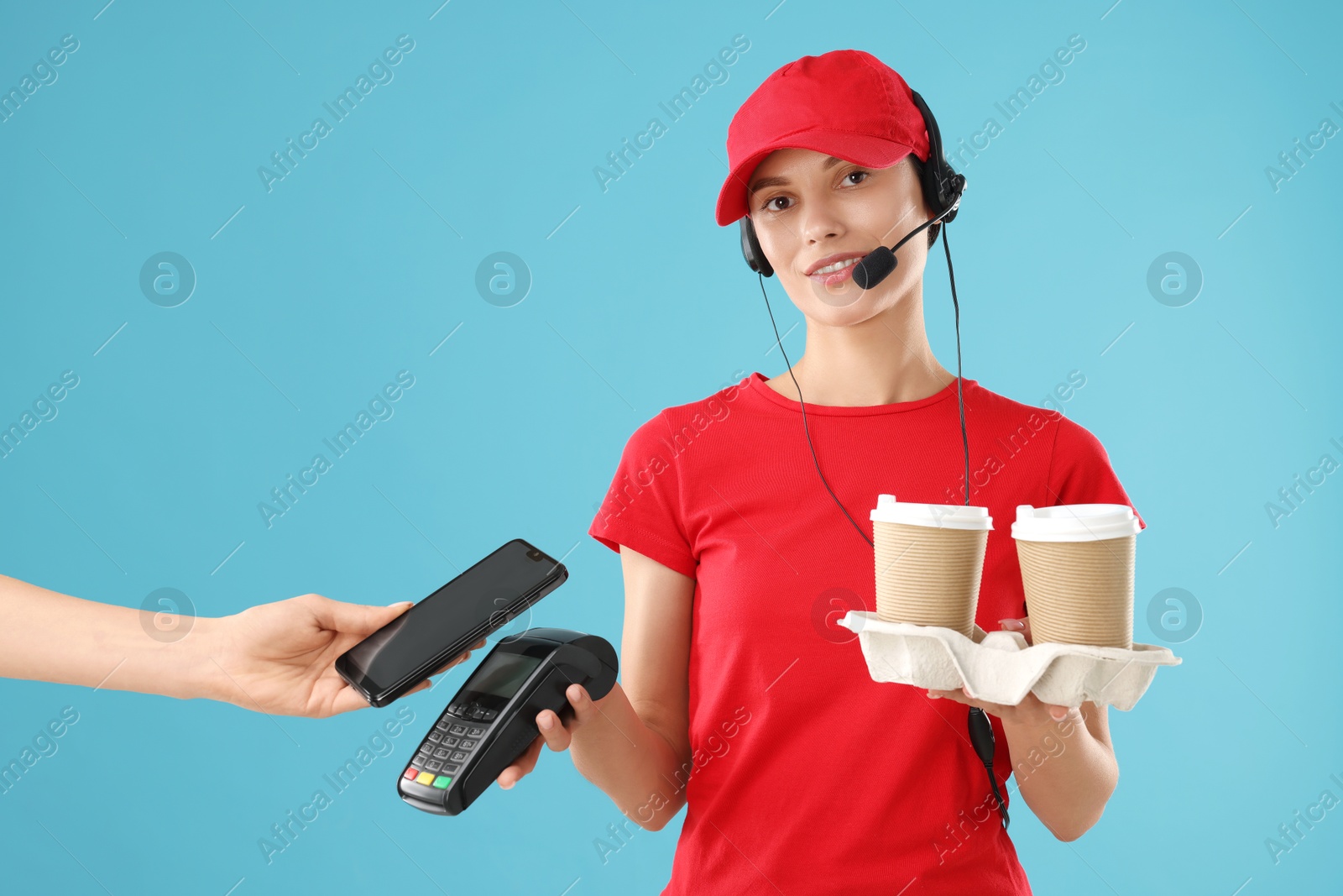 Photo of Fast-food worker taking payment from client via terminal on light blue background, closeup