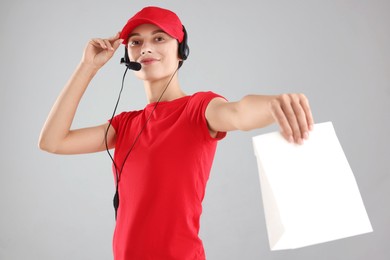 Photo of Fast-food worker with paper bag on gray background