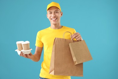 Photo of Fast-food worker with paper bags and cups on light blue background