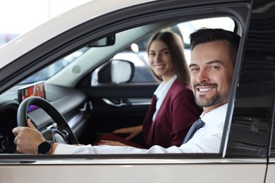 Happy saleswoman and client inside new car in salon