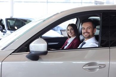 Photo of Happy saleswoman and client inside new car in salon