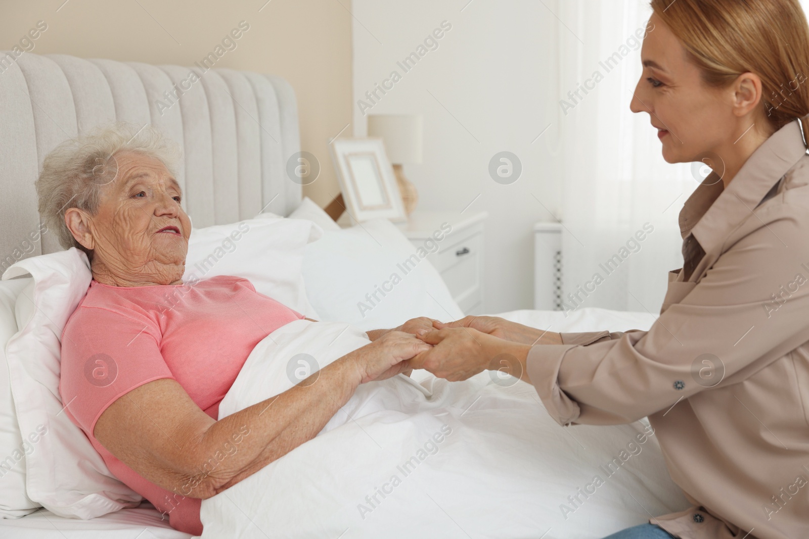 Photo of Caregiver supporting senior patient in bedroom at home